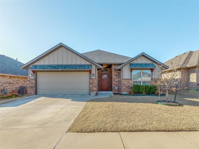 craftsman house featuring a shingled roof, concrete driveway, a garage, central air condition unit, and brick siding