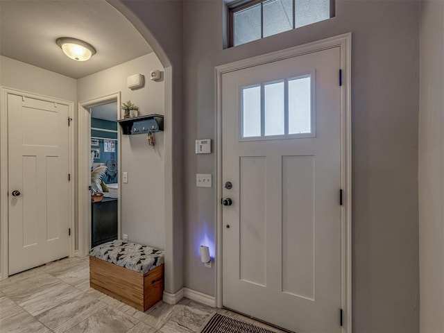 foyer featuring baseboards and arched walkways