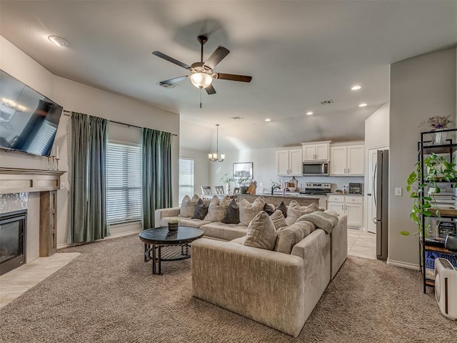 living area featuring ceiling fan with notable chandelier, recessed lighting, a fireplace, light colored carpet, and vaulted ceiling