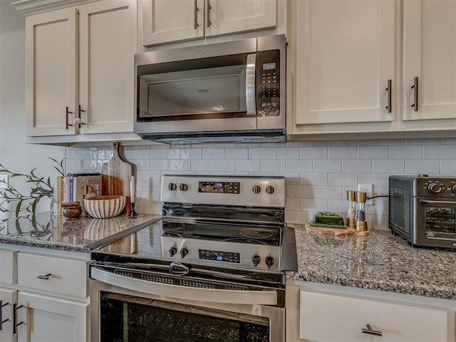 kitchen with tasteful backsplash, a toaster, stone counters, and appliances with stainless steel finishes