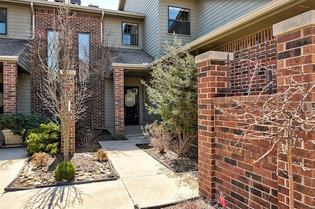 entrance to property with brick siding and roof with shingles