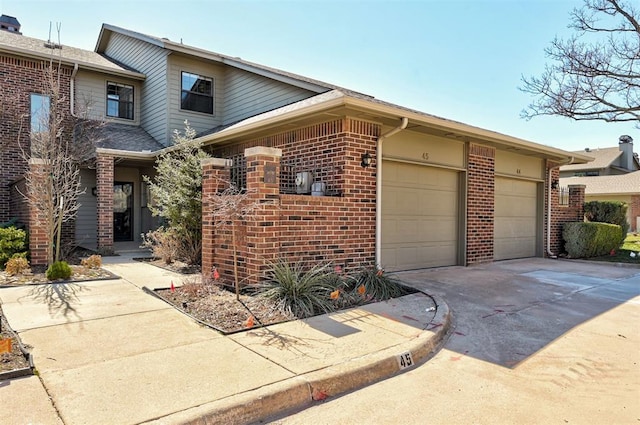 view of property exterior with a garage, brick siding, and driveway