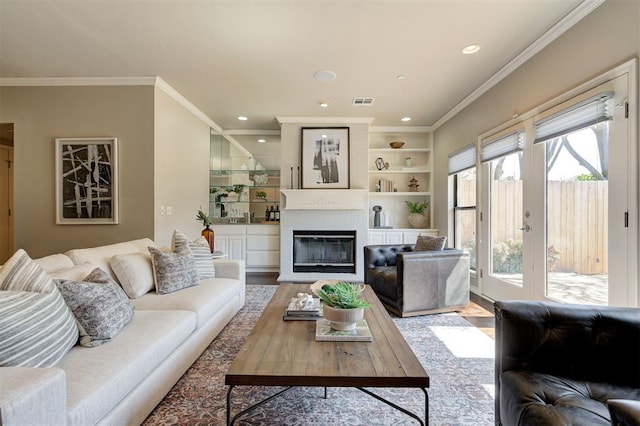 living area featuring recessed lighting, wood finished floors, a glass covered fireplace, and crown molding