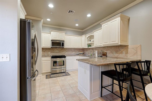 kitchen featuring visible vents, crown molding, appliances with stainless steel finishes, a peninsula, and a sink