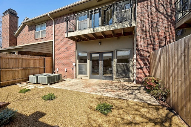 rear view of house with a jacuzzi, french doors, brick siding, central AC unit, and a patio area