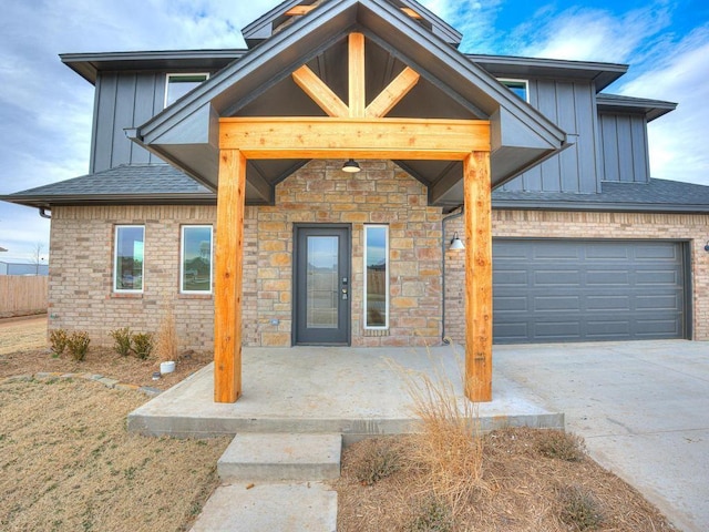 doorway to property with a shingled roof, board and batten siding, an attached garage, and concrete driveway