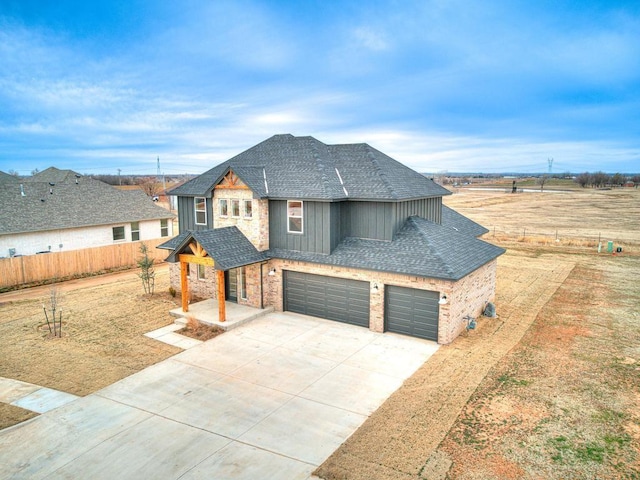 view of front of home featuring fence, a shingled roof, concrete driveway, a garage, and board and batten siding