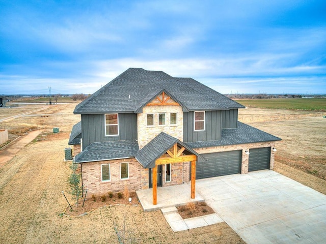 craftsman house with a shingled roof, concrete driveway, stone siding, board and batten siding, and brick siding