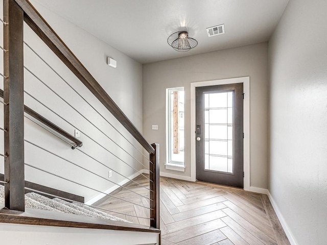 foyer entrance with stairs, baseboards, and visible vents