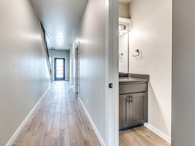 hallway featuring light wood finished floors and baseboards