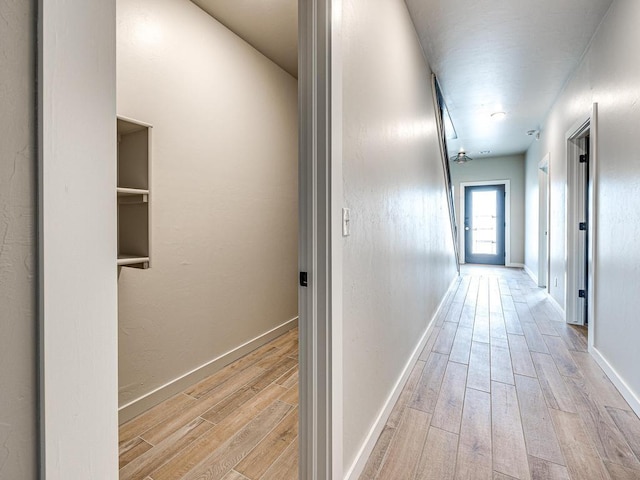 corridor featuring baseboards and light wood finished floors