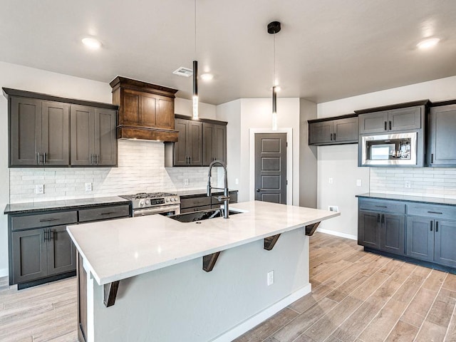 kitchen featuring light wood finished floors, stainless steel appliances, a breakfast bar, and a sink