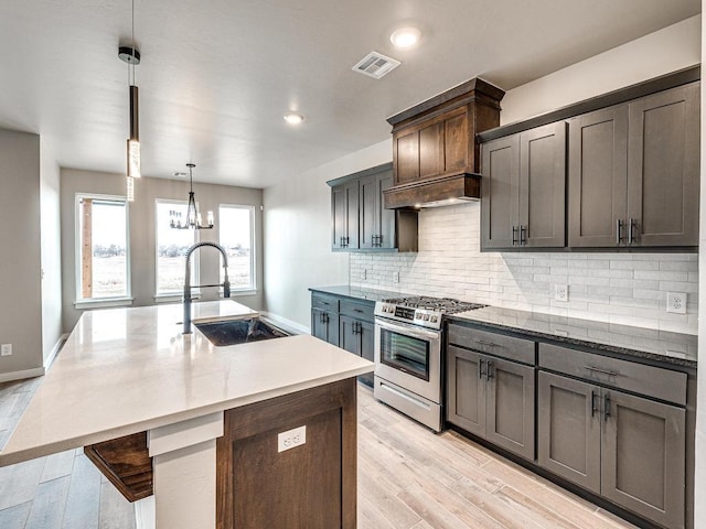 kitchen with visible vents, a sink, tasteful backsplash, custom exhaust hood, and stainless steel range with gas stovetop