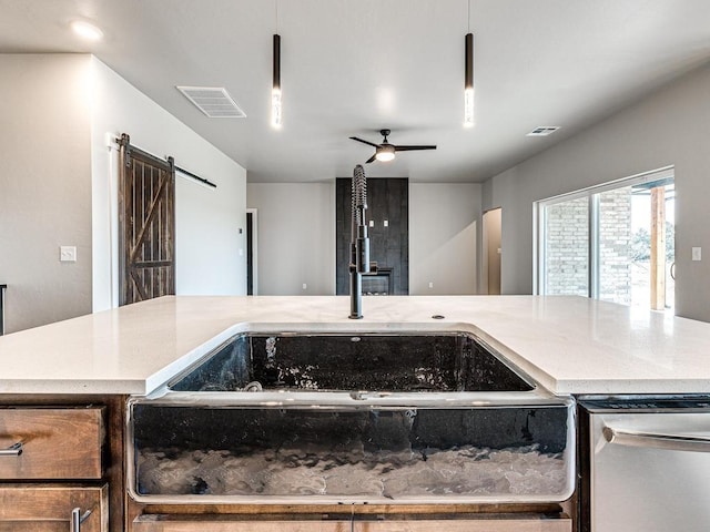 kitchen featuring a sink, visible vents, a barn door, and a ceiling fan