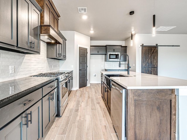 kitchen with visible vents, light wood finished floors, a sink, appliances with stainless steel finishes, and a barn door