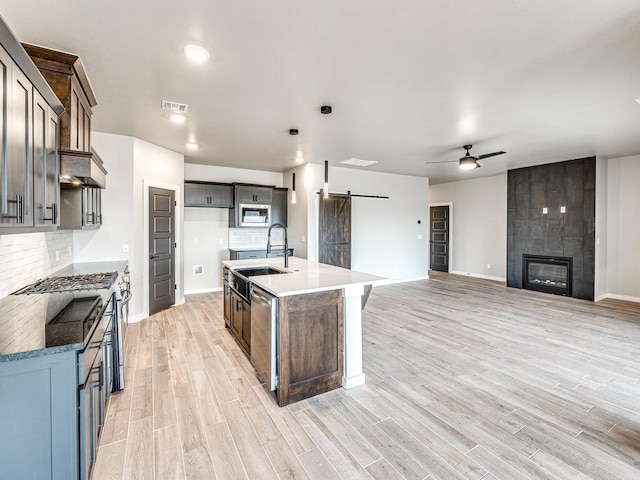 kitchen featuring light wood-type flooring, visible vents, a sink, tasteful backsplash, and a barn door