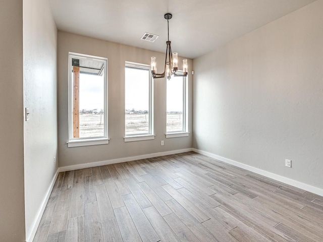 unfurnished room with wood finished floors, a healthy amount of sunlight, visible vents, and baseboards