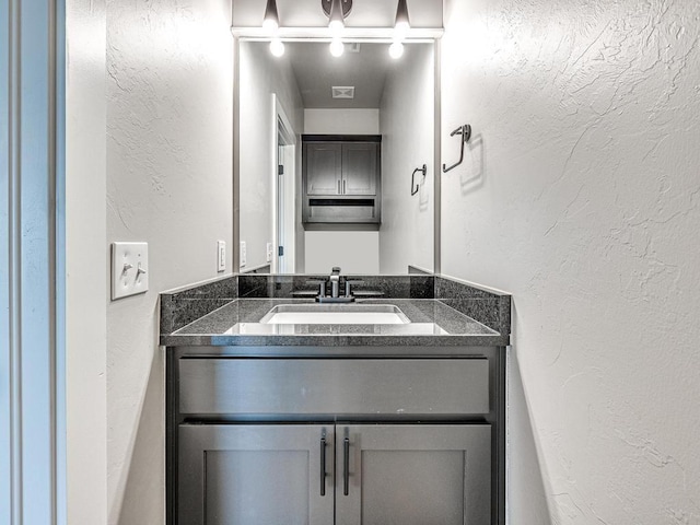 bathroom with visible vents, vanity, and a textured wall