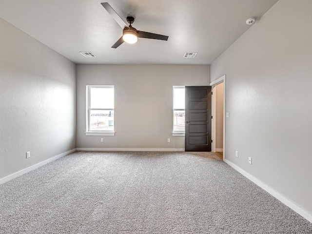 empty room with carpet flooring, plenty of natural light, and visible vents