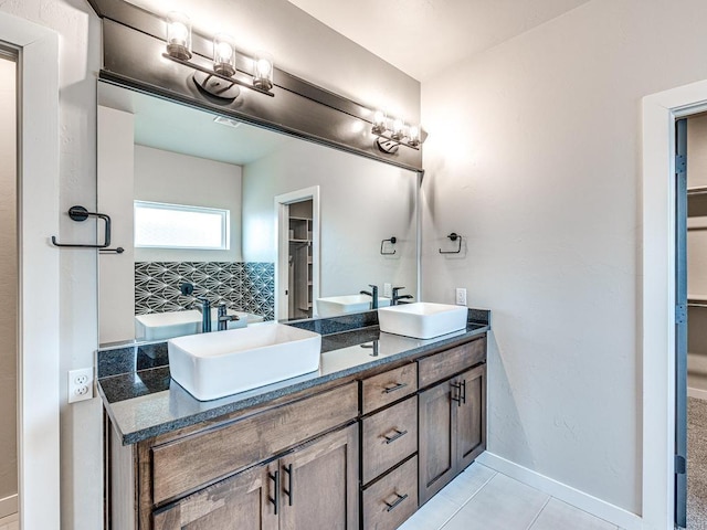 bathroom with tile patterned flooring, double vanity, baseboards, and a sink