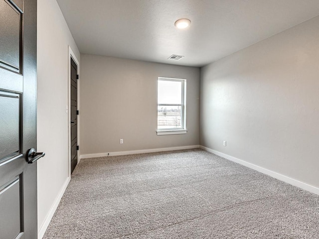 carpeted spare room with visible vents and baseboards