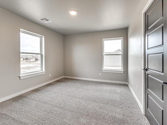 empty room with visible vents, plenty of natural light, carpet, and baseboards