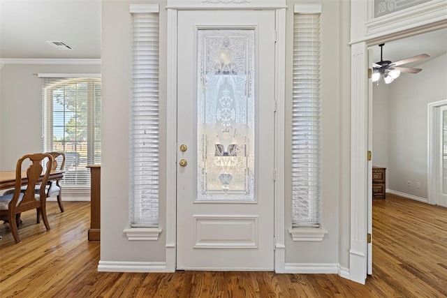 foyer entrance featuring crown molding, wood finished floors, visible vents, and ceiling fan