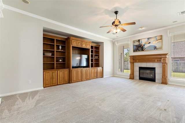 unfurnished living room with light colored carpet, ceiling fan, crown molding, and a tile fireplace