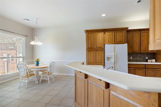 kitchen with visible vents, backsplash, light countertops, light tile patterned floors, and white refrigerator with ice dispenser