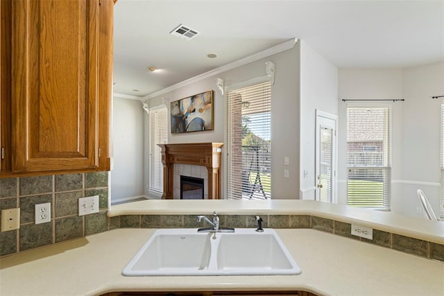 kitchen with brown cabinetry, visible vents, a fireplace, a sink, and light countertops