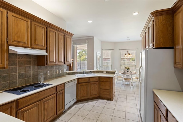 kitchen featuring under cabinet range hood, white appliances, and brown cabinetry