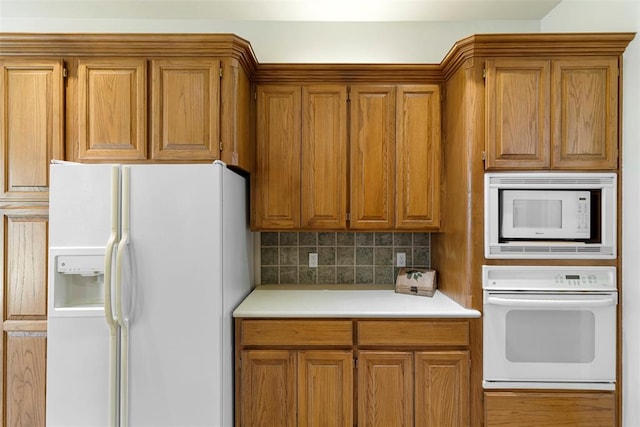 kitchen featuring white appliances, brown cabinets, and backsplash