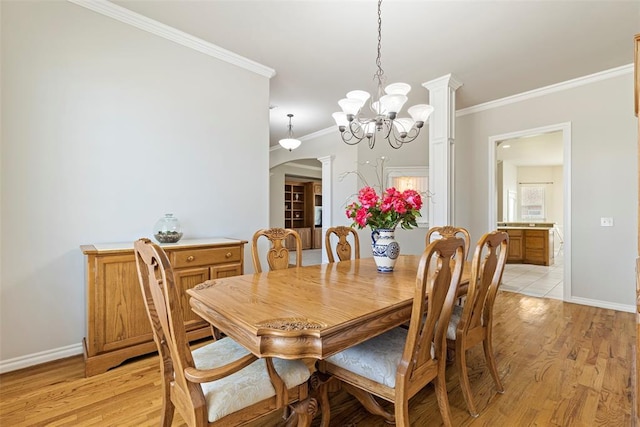 dining area featuring baseboards, a chandelier, light wood-type flooring, ornamental molding, and arched walkways