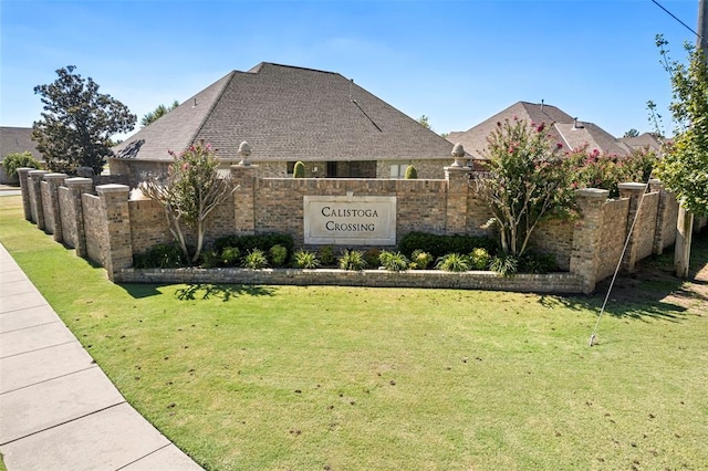 community / neighborhood sign featuring a lawn and fence