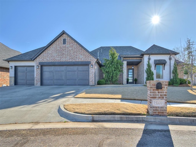 view of front of home with brick siding, an attached garage, a shingled roof, and driveway