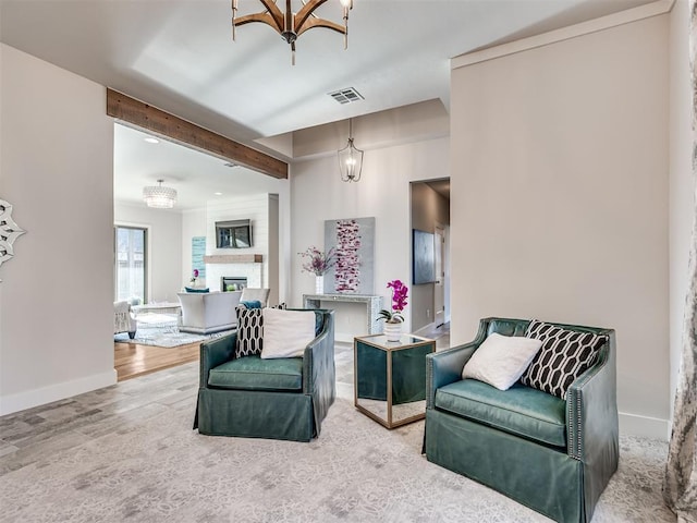 living room featuring visible vents, baseboards, a chandelier, a fireplace, and wood finished floors