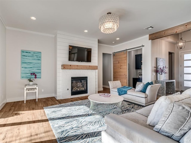 living room featuring a notable chandelier, visible vents, ornamental molding, and wood finished floors