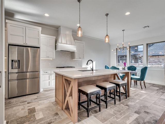 kitchen featuring visible vents, an inviting chandelier, custom exhaust hood, stainless steel fridge with ice dispenser, and a sink