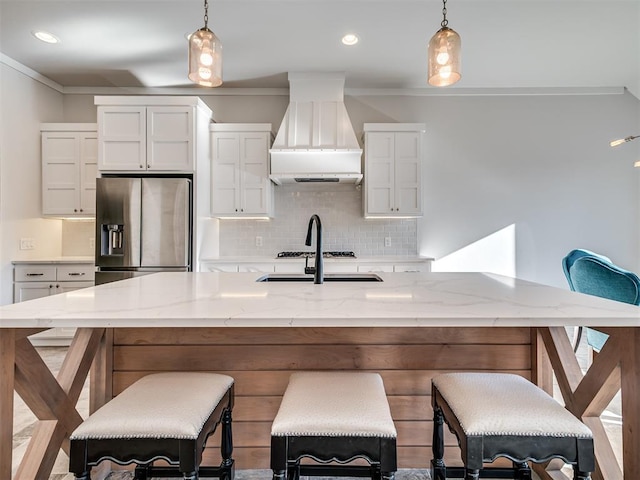 kitchen with stainless steel fridge, pendant lighting, custom range hood, and ornamental molding