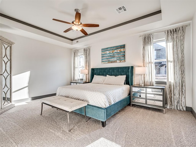 bedroom featuring a tray ceiling, carpet floors, and visible vents