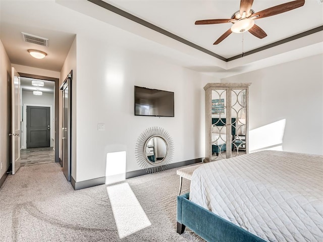 bedroom with visible vents, light carpet, baseboards, a raised ceiling, and ceiling fan