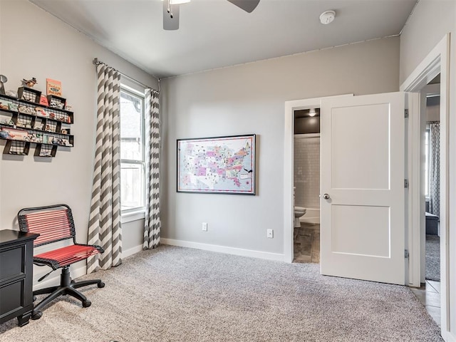 carpeted office space featuring baseboards and a ceiling fan