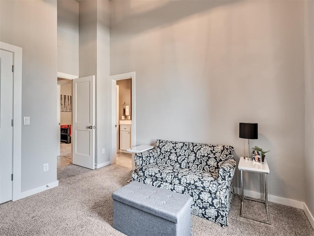 sitting room with baseboards, carpet floors, and a high ceiling