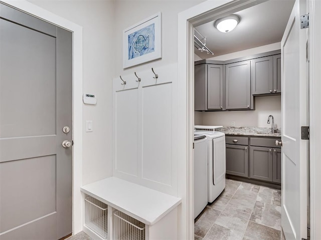 laundry room featuring stone finish flooring, cabinet space, independent washer and dryer, and a sink