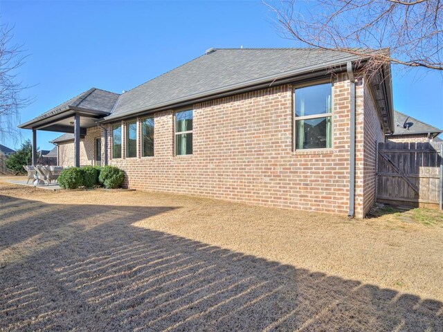 back of house with fence, brick siding, and a shingled roof