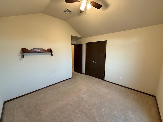 unfurnished bedroom featuring visible vents, light colored carpet, baseboards, and vaulted ceiling