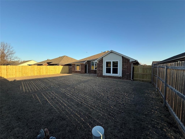 back of house featuring a fenced backyard and brick siding