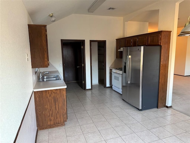 kitchen with visible vents, a sink, white gas range oven, stainless steel fridge, and vaulted ceiling