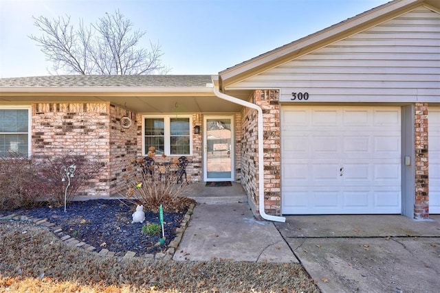 doorway to property with a garage, stone siding, roof with shingles, and concrete driveway