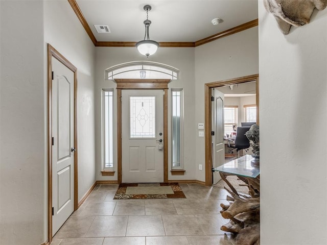 foyer entrance with light tile patterned floors, baseboards, visible vents, and ornamental molding